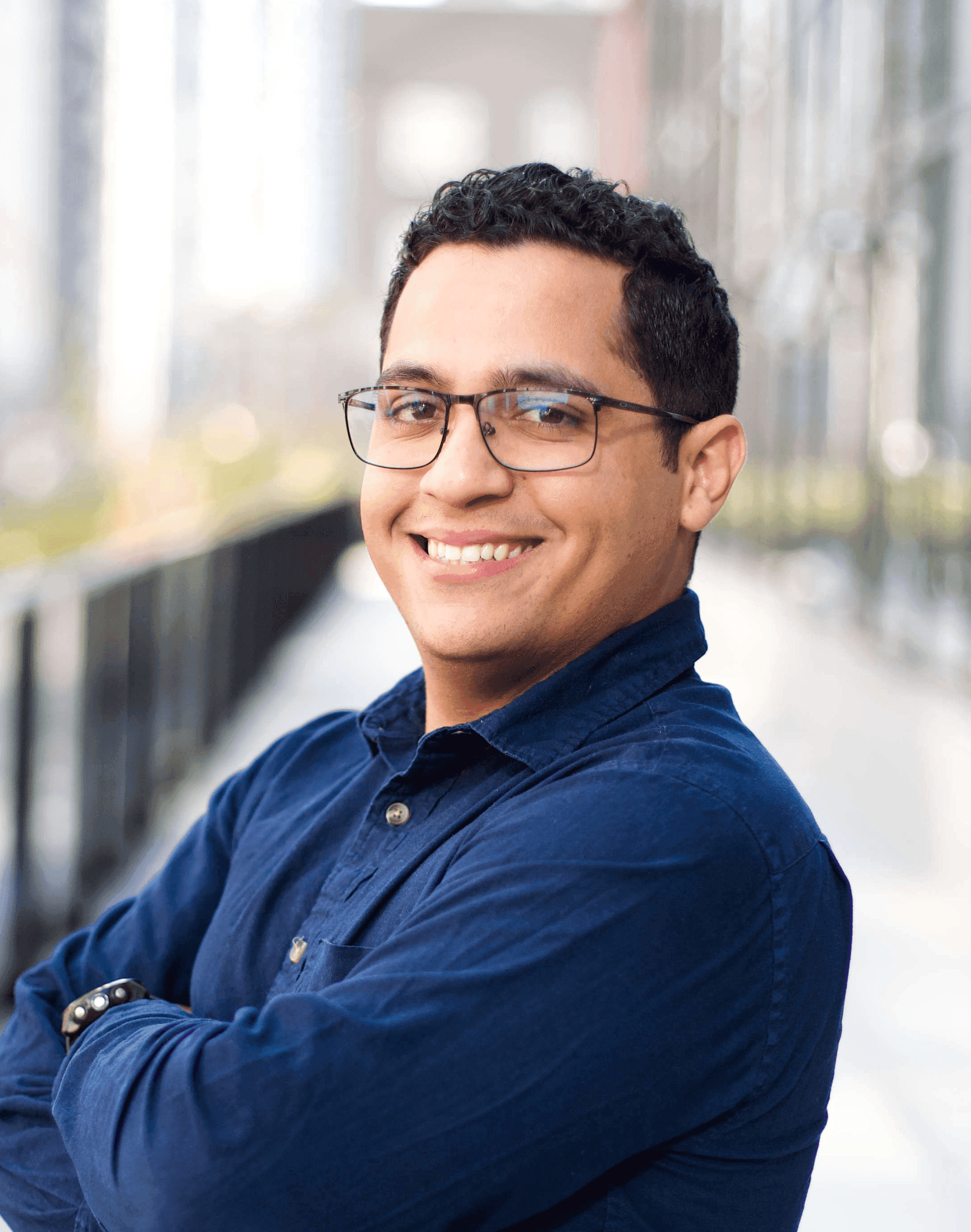 Victor Dantas, smiling with arms crossed on a city walkway.
